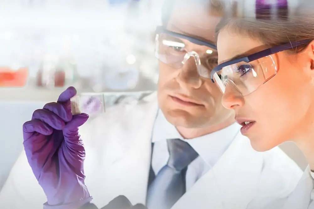 Twarze kobiety i mężczyzny patrzących na próbkę w laboratorium