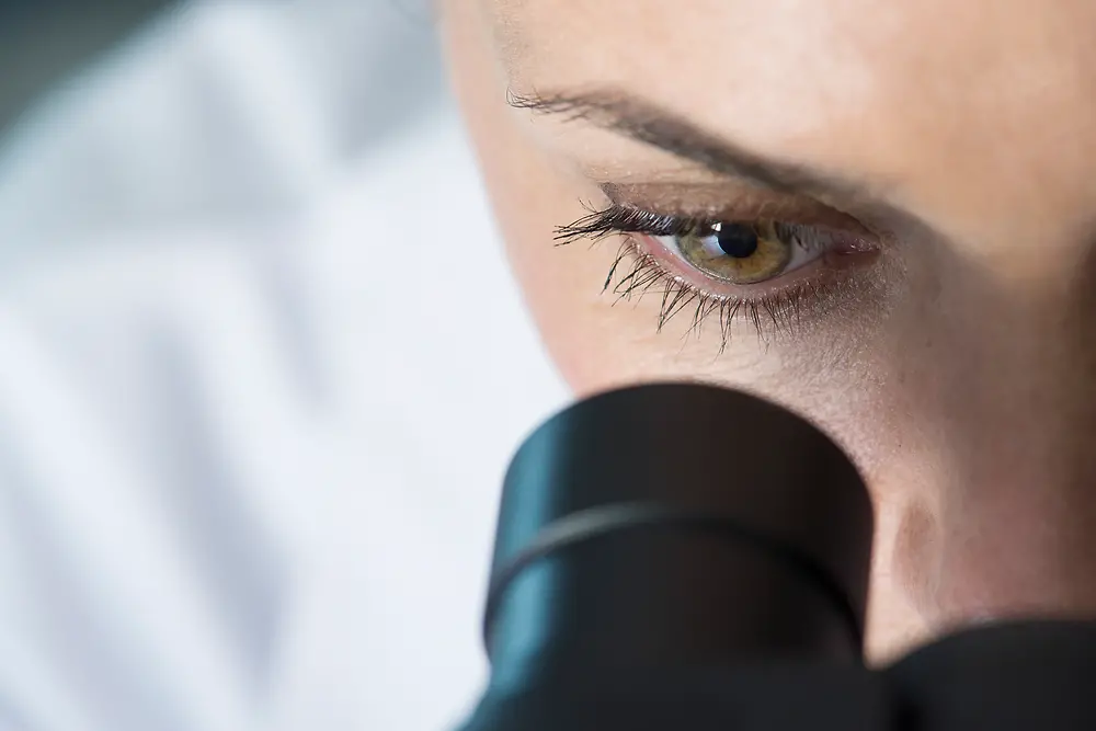 Oko kobiety patrzącej przez mikroskop