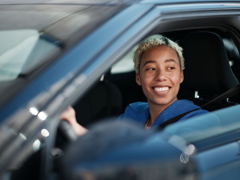 Eine Fahrerin sitzt in ihrem E-Auto und lächelt
