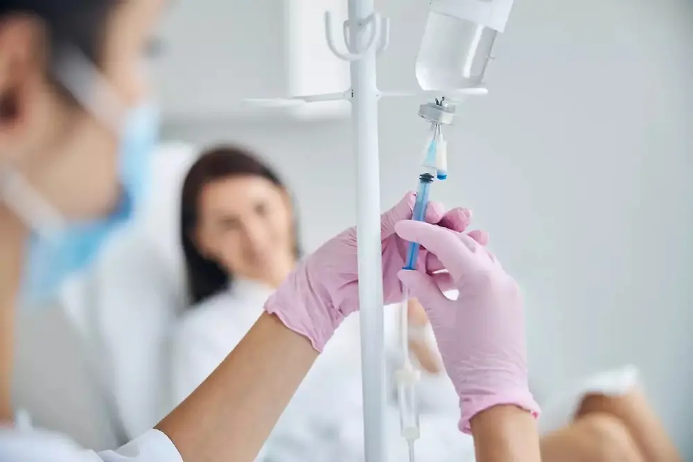 Pracownik służby zdrowia trzymający worek z kroplówką dożylną w placówce służby zdrowia.