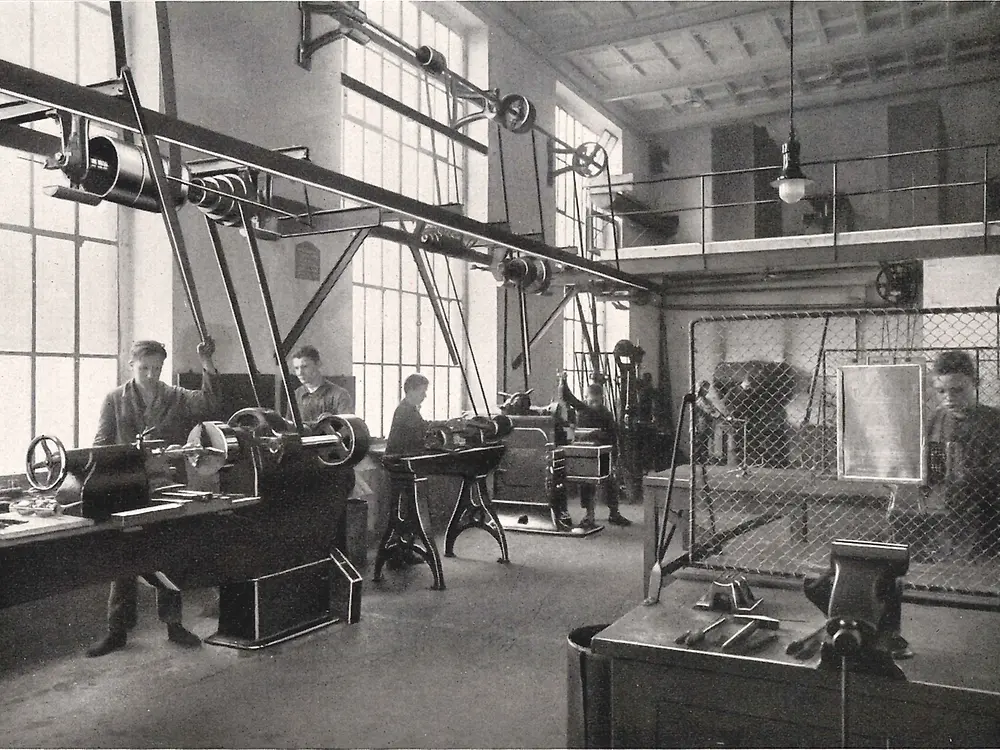 Praktykanci obsługują maszyny w warsztacie obróbki metalu.