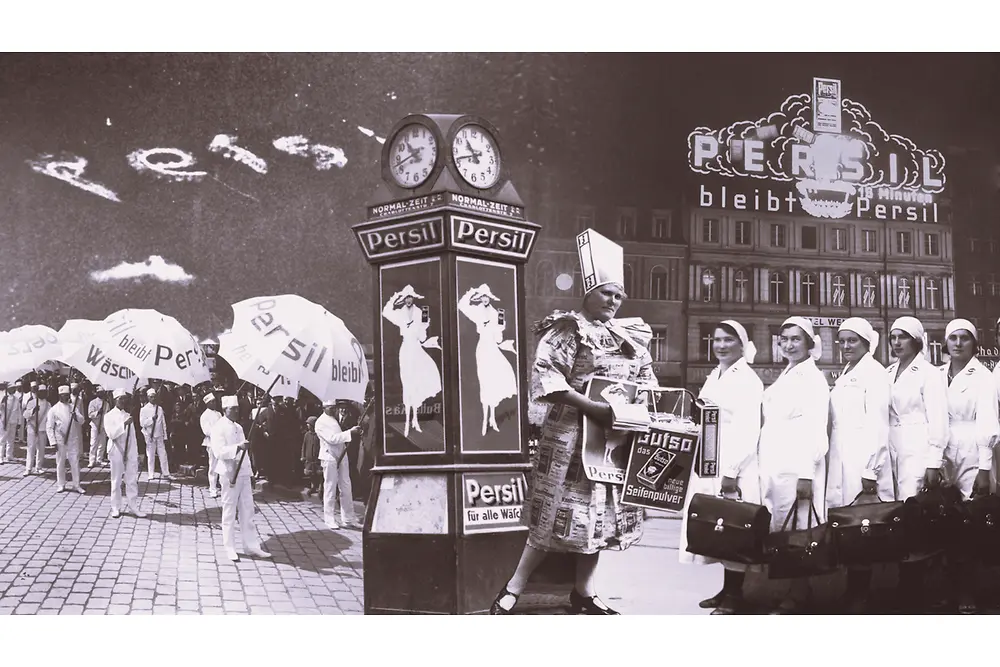 Kolaż reklamowy Persil w stylu retro, przedstawiający ludzi z parasolami z logo marki, zegar z plakatami oraz budynek z podświetlanym szyldem Persil w tle.