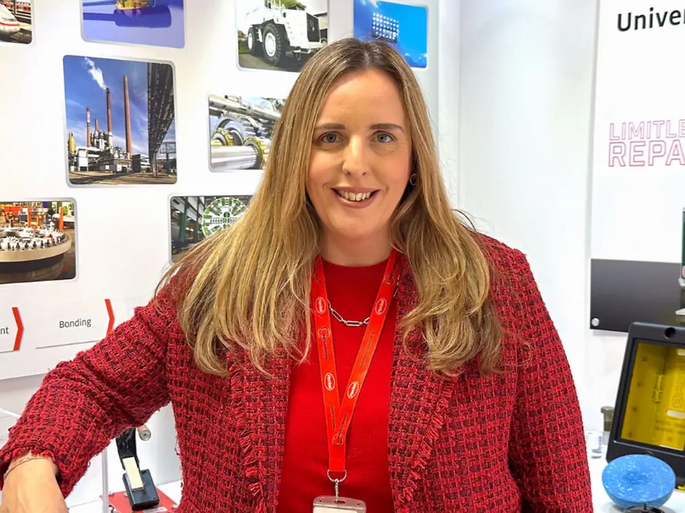 Employee standing at Henkel LOCTITE exhibition booth showcasing industrial adhesive products and applications.